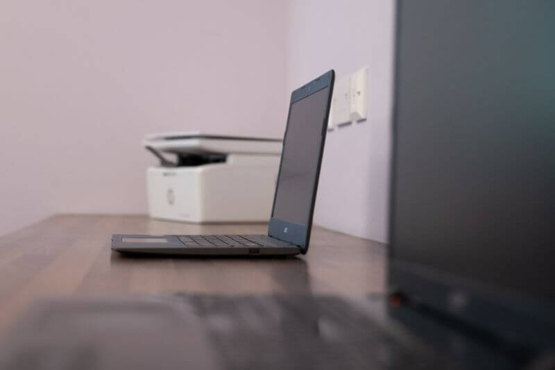 Laptop with printer on desk.