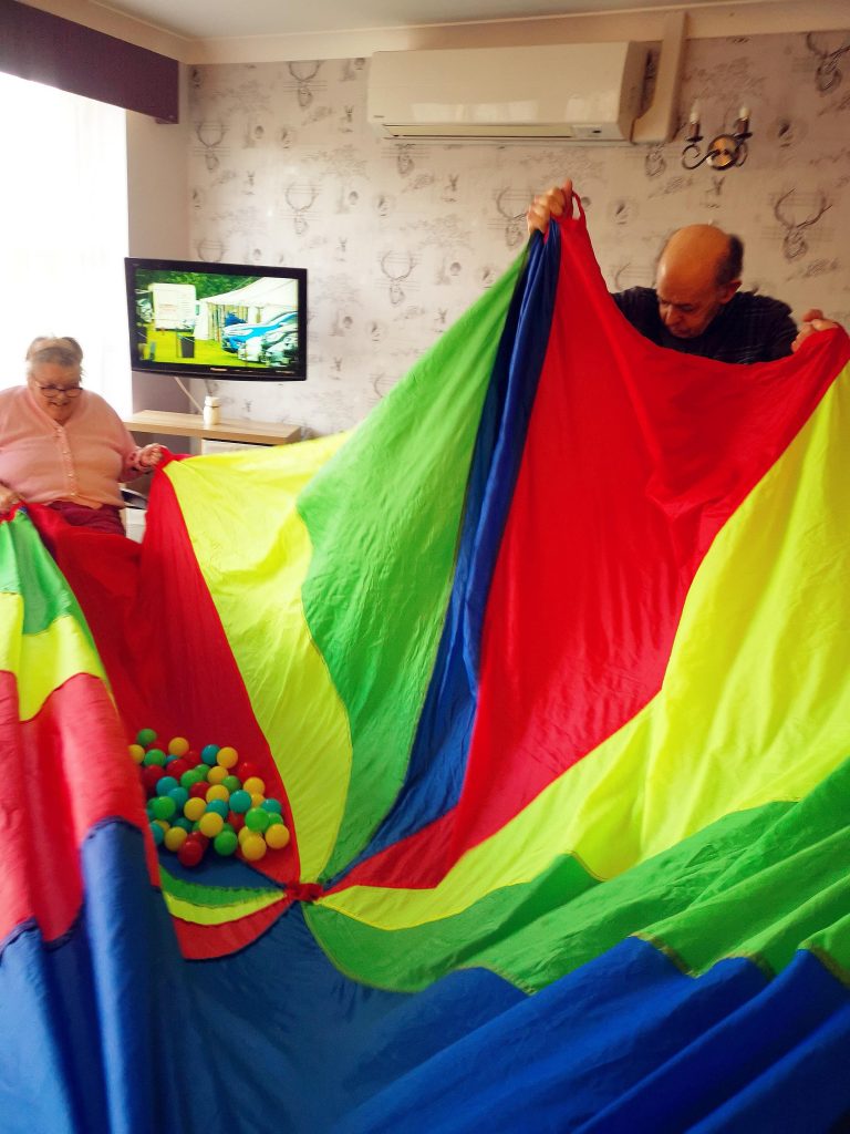 Two resident playing with a colour blanket and balls game.