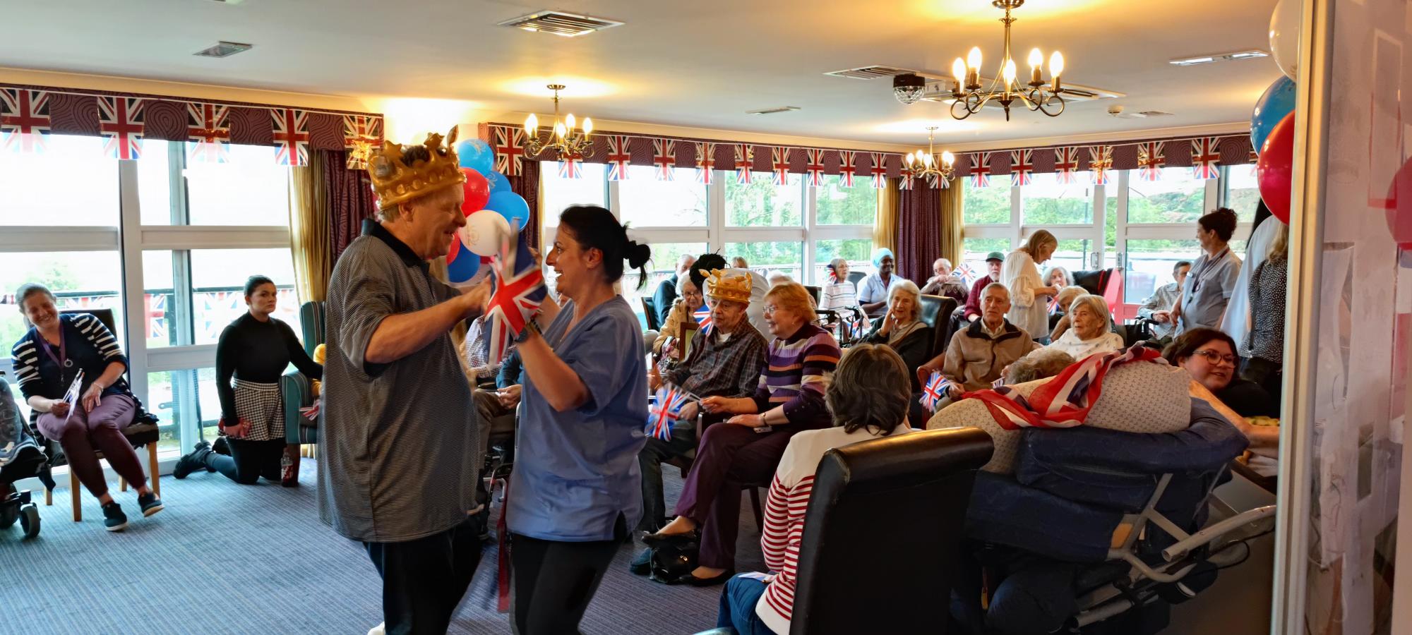A group of resident enjoying the Kings coronation celebrations and a resident and a carer dancing.