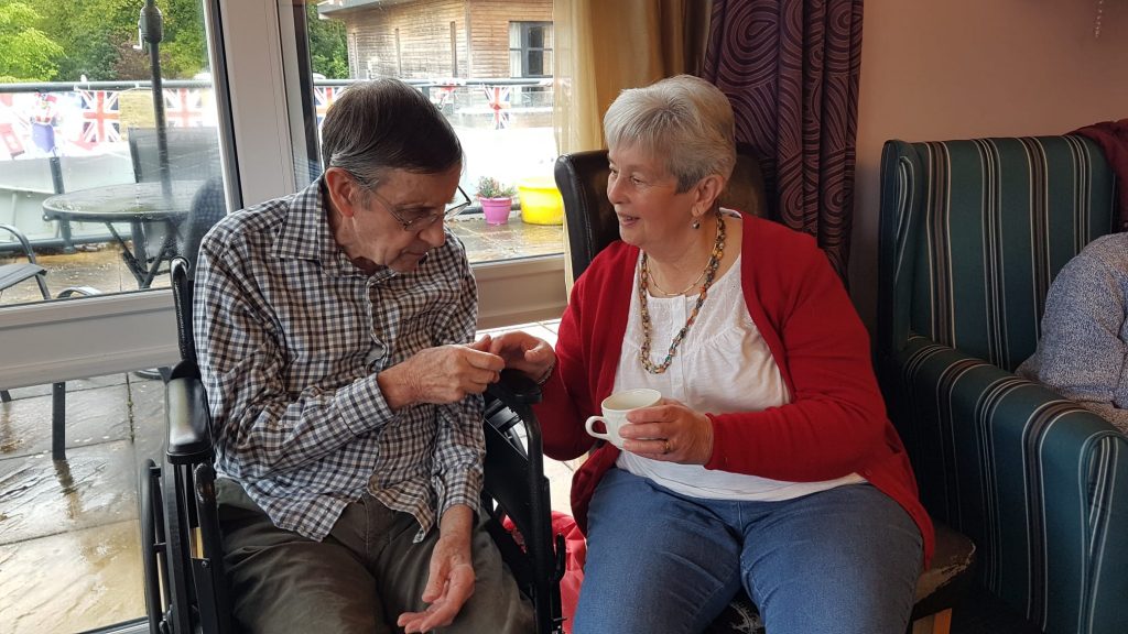 Two people holding hands talking over a cup of tea.