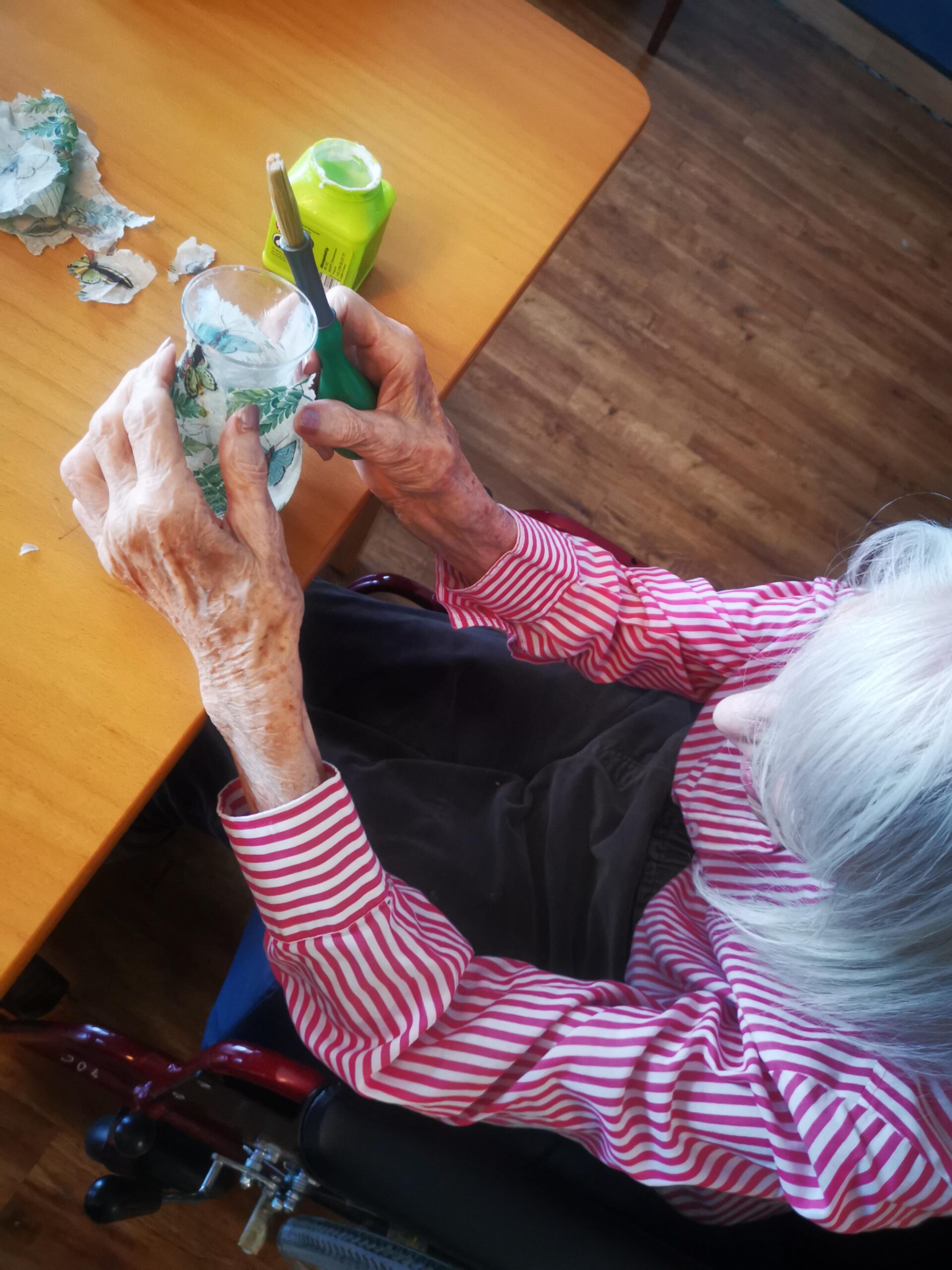 A female resident in a striped shirt decorating a glass.