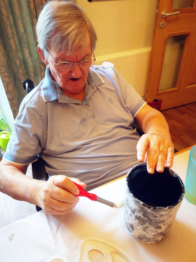 A male resident painting a pot.