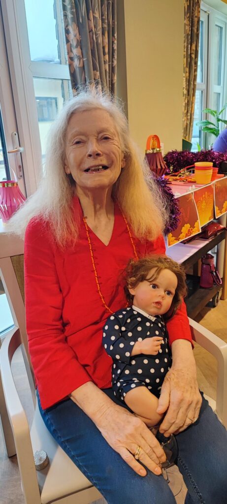 a female resident holding a doll and smiling