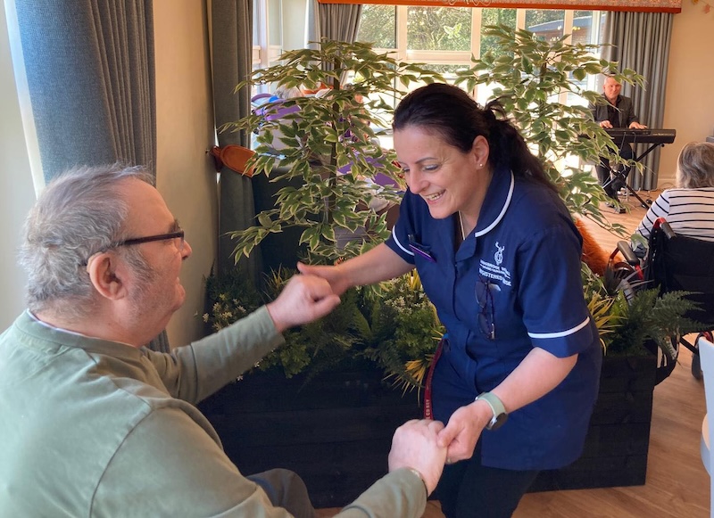 resident and carer holding hands and dancing