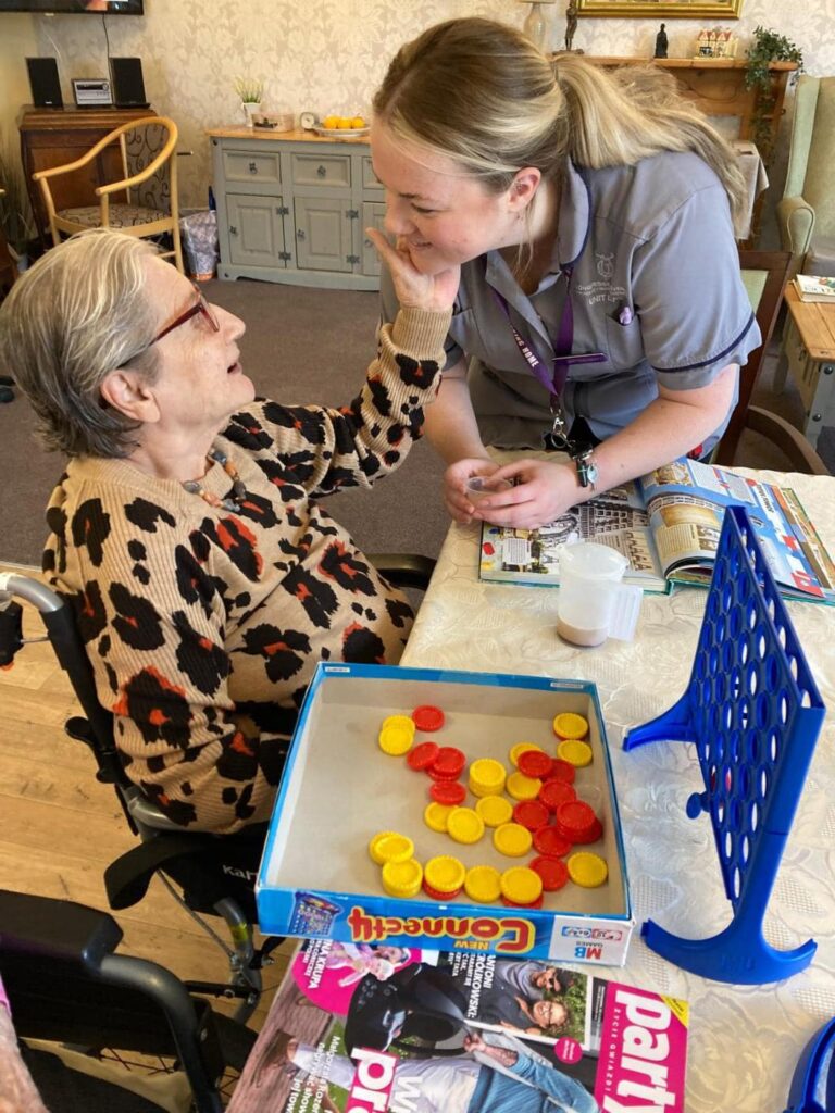 resident and carer playing connect 4 together