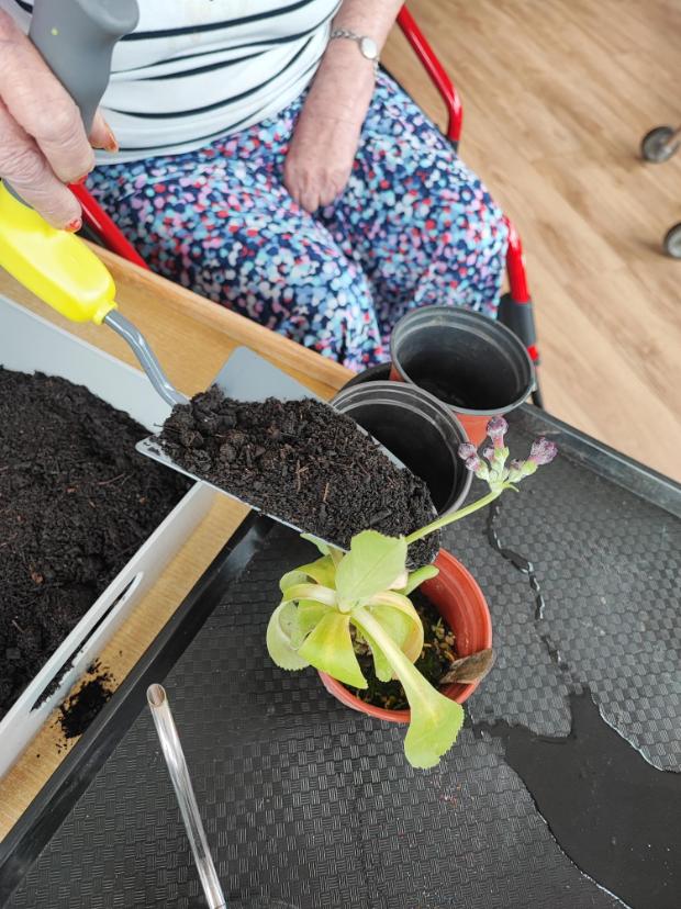a resident filling a pot with soil