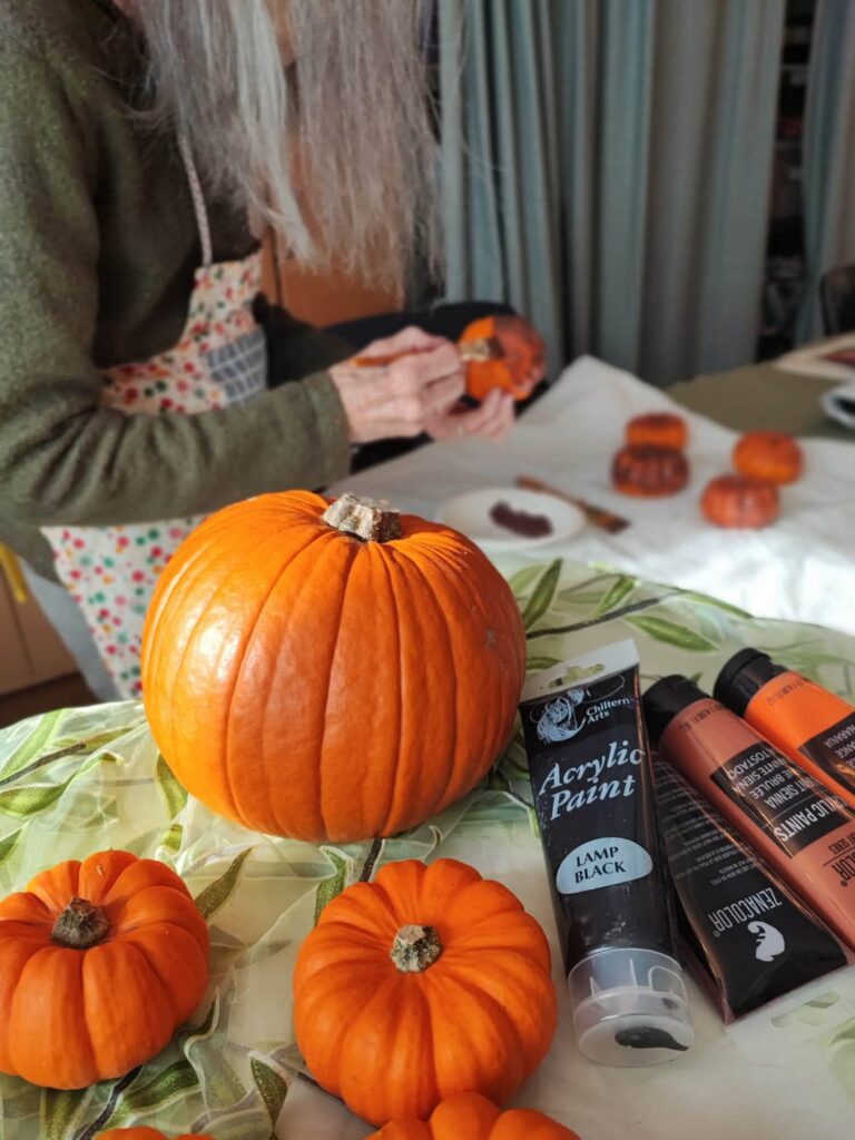pumpkin with an older lady painting behind